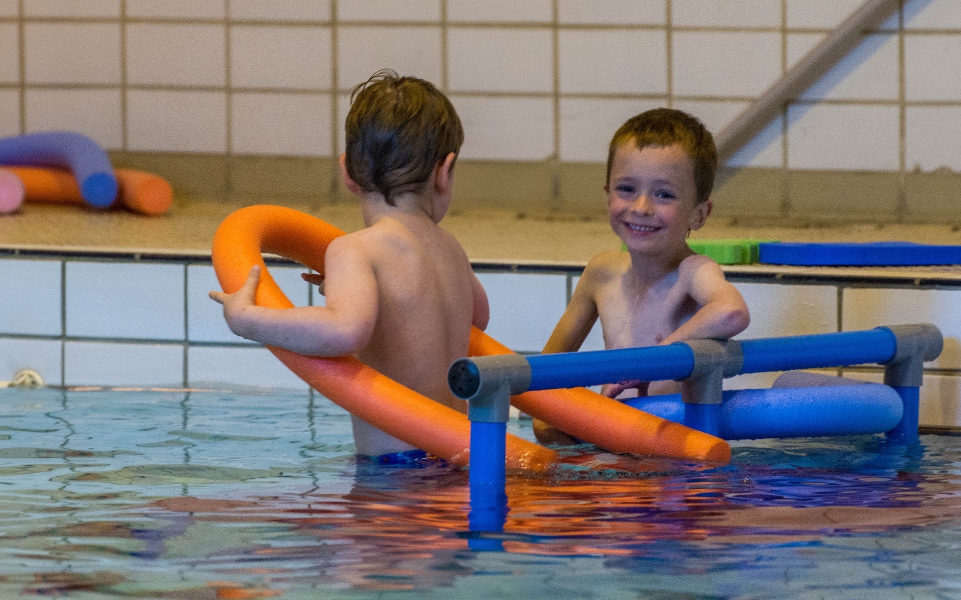 Small boys in pool with noodles